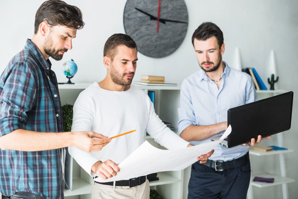 Dress Männer betrachten Baupläne in einem Büro.