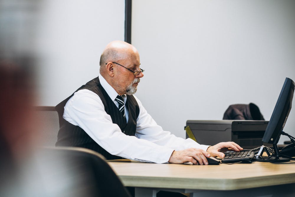 Ein Mann sitzt an einem Tisch und arbeitet an einem Laptop.