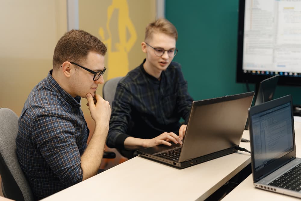 Zwei Personen sitzen zusammen an einem Laptop.