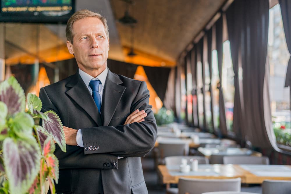 Ein Geschäftsmann steht mit verschränkten Armen in einem Restaurant.